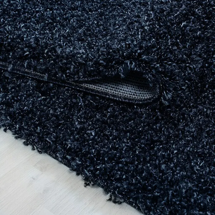 Hochflorteppich Life 1500Navy, 200 x 100 cm, 100% Polypropylen - Nahaufnahme eines dunkelblauen Shaggy-Teppichs mit umgeschlagener Ecke, der seine rutschfeste Unterseite zeigt.