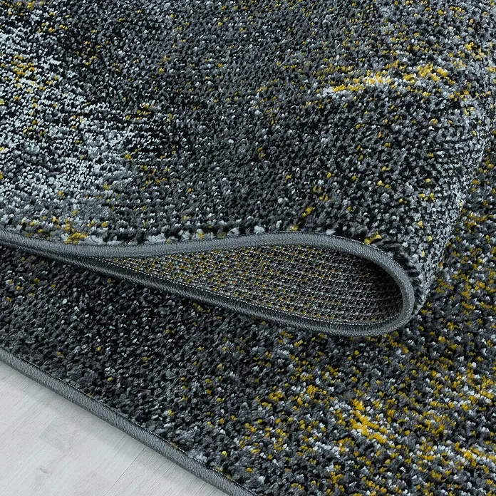Kurzflorteppich Ottawa 4203 - Gelb, 150 x 80 cm, 100 % Polypropylen - Detailaufnahme eines grauen Teppichs mit gelben Akzenten, der eine weiche Textur und eine umgeschlagene Ecke zeigt.