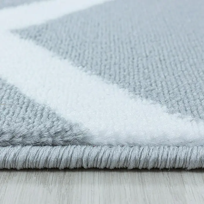Kurzflorteppich Costa 3524Grau, 230 x 160 cm, 100 % Polypropylen - Nahaufnahme eines modernen grauen Teppichs mit weißem Zickzackmuster und sauberer Kante, ideal für ein stilvolles Zuhause.