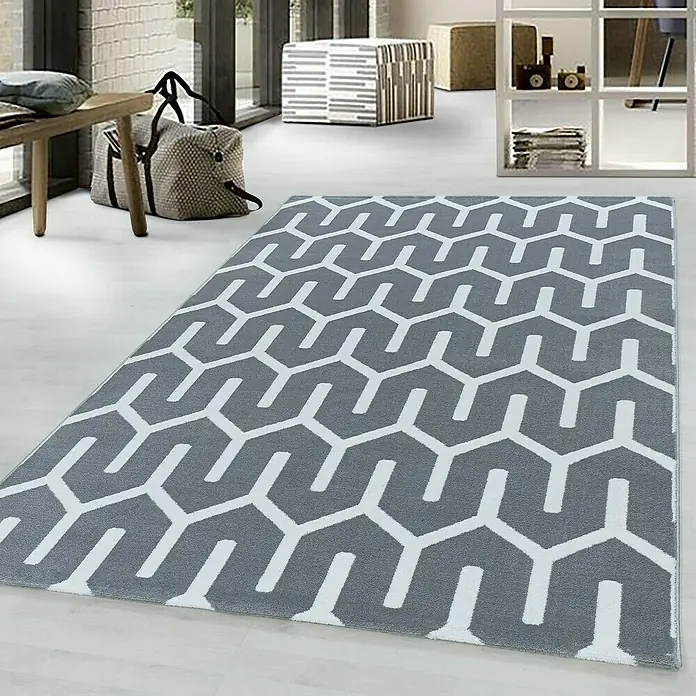 Kurzflorteppich Costa 3524 - Grau, 200 x 140 cm, 100 % Polypropylen - Ein grauer Teppich mit einem modernen, geometrischen Muster in Weiß liegt in einem hellen Raum. Der Teppich verleiht dem Raum eine stilvolle Note.