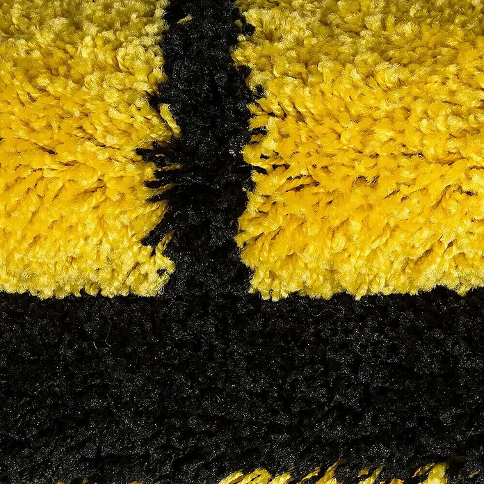 Kinderteppich Fun 6001 - Gelb, Durchmesser: 100 cm, 100% Polypropylen - Detailaufnahme eines Teppichs mit einem auffälligen gelb-schwarzen Streifenmuster, das eine interessante Textur und Farbkombination zeigt.