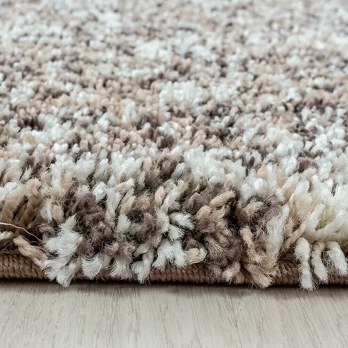 Hochflorteppich Enjoy 4500 - Beige, 370 x 280 cm, 100 % Polypropylen - Nahaufnahme eines beigen und weißen Shaggy-Teppichs, der seine weiche Textur und das gemütliche Aussehen hervorhebt.\n