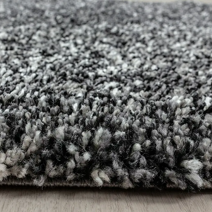Hochflorteppich Enjoy 4500Anthrazit, 110 x 60 cm, 100% Polypropylen - Nahaufnahme eines grauen Teppichs mit hohem Flor, der Weichheit und Komfort ausstrahlt, ideal für Wohnräume, Textur und Wärme vereint.