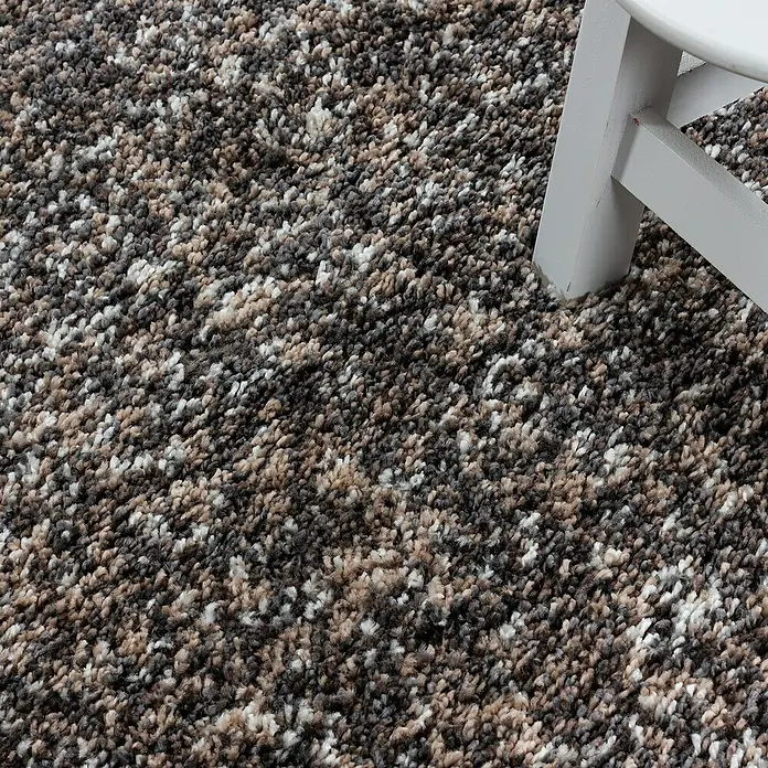 Hochflorteppich Enjoy 4500Taupe, 250 x 80 cm, 100 % Polypropylen - Nahaufnahme eines Teppichs mit mehrfarbigen Fasern und einem weißen Stuhlbein.