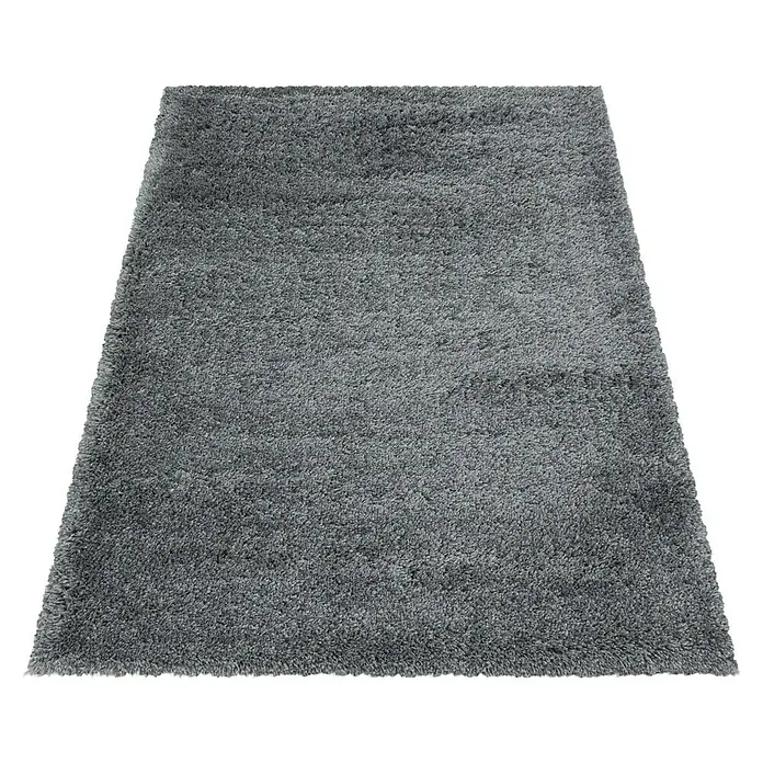 Hochflorteppich Fluffy 3500Light Grey, 370 x 380 cm, 100% Polypropylen - Ein grauer, rechteckiger Shaggy-Teppich liegt auf einem schwarzen Hintergrund. Der Teppich hat einen dicken, weichen Flor.