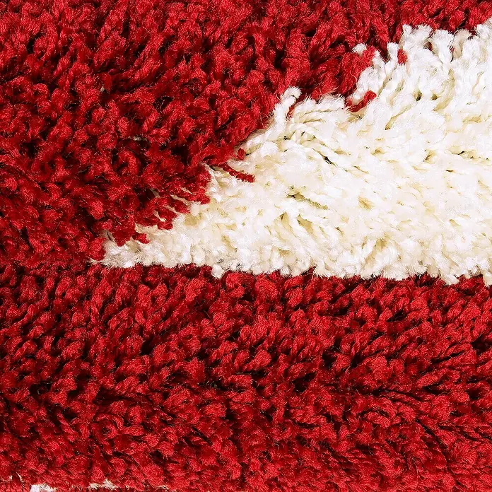 Kinderteppich Fun 6001Rot, Durchmesser: 120 cm, 100% Polypropylen - Nahaufnahme eines roten und weißen Teppichs mit hochfloriger Textur, der Komfort und Wärme ausstrahlt. Ein weicher Blickfang für jeden Raum.