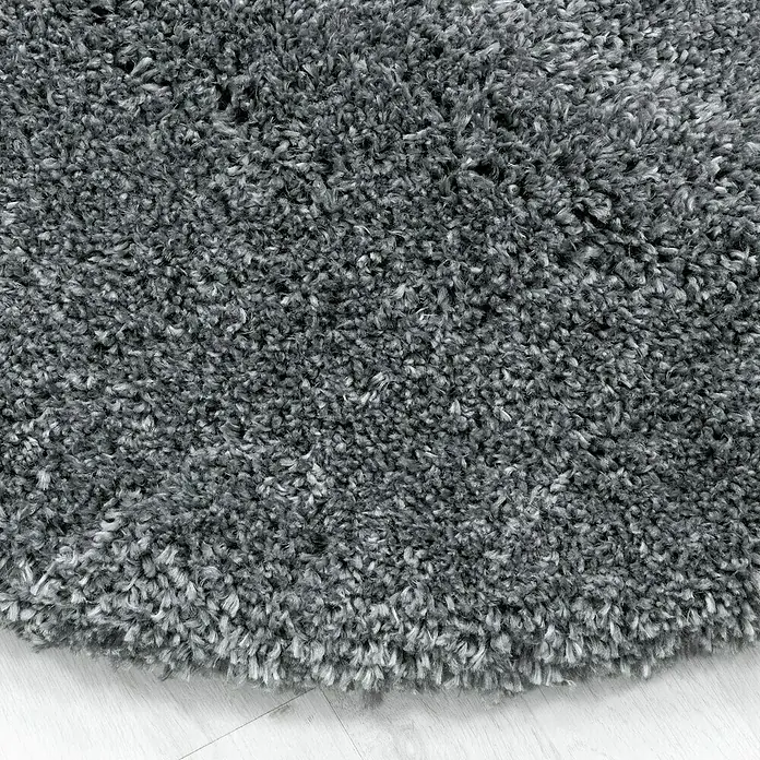 Hochflorteppich Fluffy 3500 - Light Grey, 340 x 240 cm, 100 % Polypropylen - Nahaufnahme eines grauen, flauschigen Hochflorteppichs auf hellem Holzboden, der eine gemütliche und einladende Atmosphäre schafft.