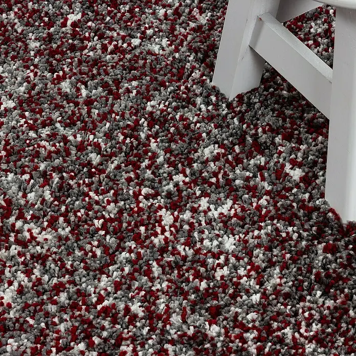 Hochflorteppich Enjoy - Rot, Durchmesser: 80 cm, 100 % Polypropylen - Detailaufnahme eines roten, grauen und weißen Teppichs mit einem Stuhlbein im Bild.