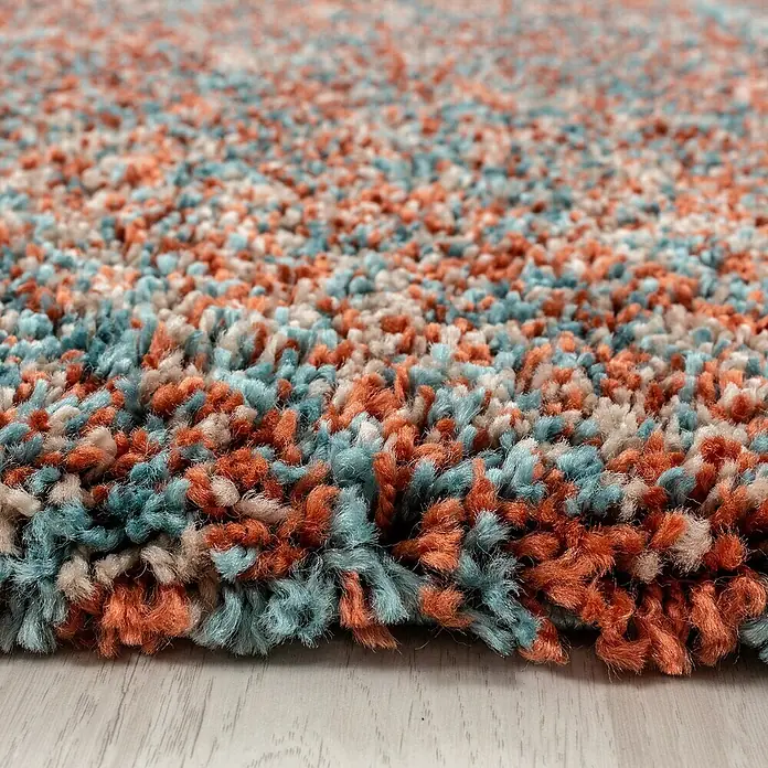Hochflorteppich Enjoy 4500Terrakotta, 170 x 120 cm, 100 % Polypropylen - Nahaufnahme eines mehrfarbigen, hochflorigen Teppichs mit orangefarbenen, blauen und cremefarbenen Farbtönen, der eine weiche und einladende Textur zeigt.