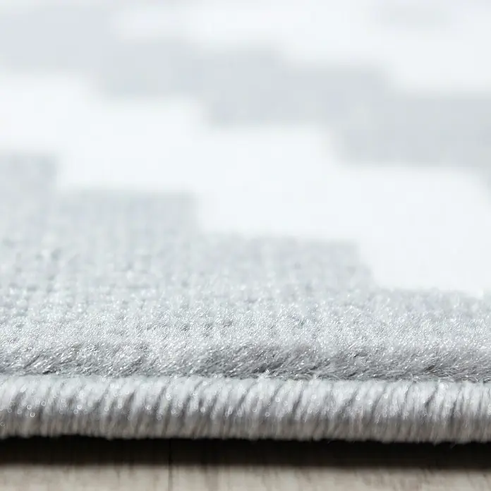 Kurzflorteppich Plus - Grau/Weiß, 340 x 240 cm, 100 % Polypropylen - Detailaufnahme eines grauen Teppichs mit geometrischem Muster, der eine weiche Textur und eine saubere Kante zeigt.