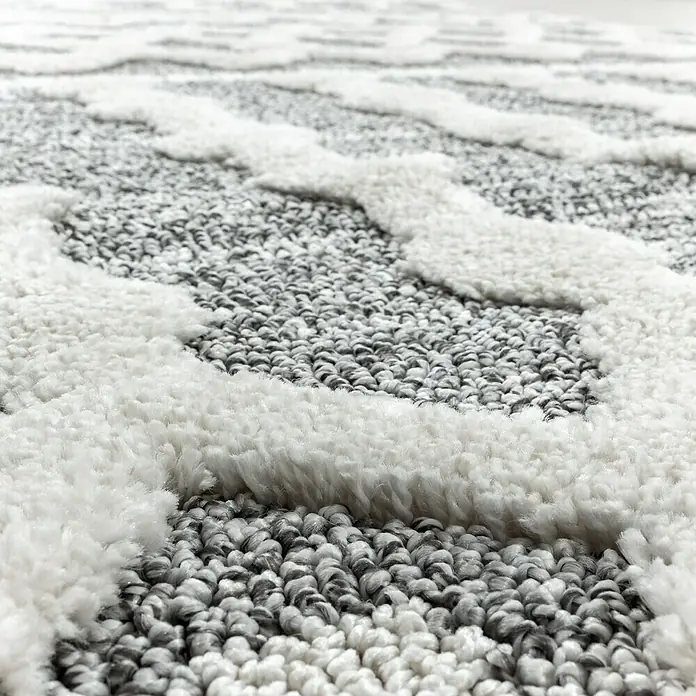 Hochflorteppich Pisa 4710Grau, 200 x 140 cm, 100 % Polypropylen - Nahaufnahme eines Teppichs mit einem gewebten Muster aus Grau- und Weißtönen, der eine weiche und einladende Textur zeigt.