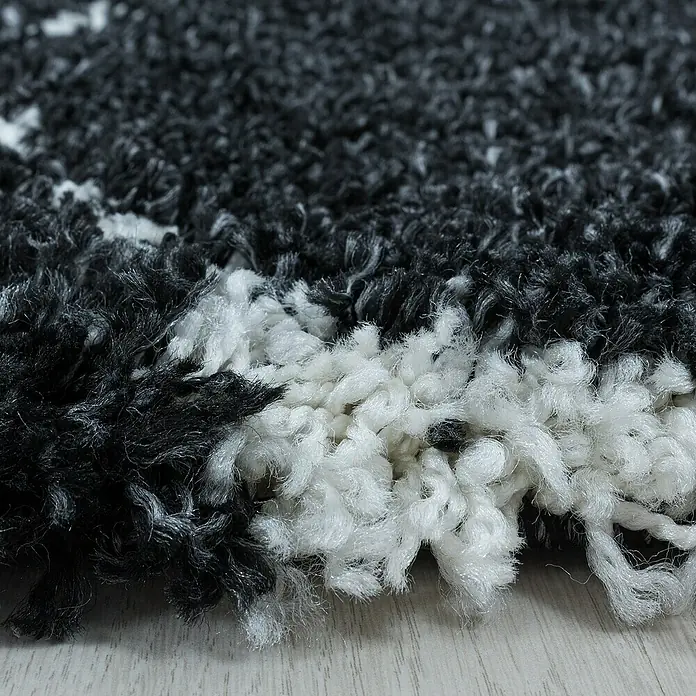 Hochflorteppich Salsa 3201Anthrazit, 290 x 200 cm, 100% Polypropylen - Nahaufnahme eines schwarz-weißen Teppichs mit hochflorigem Zottelmuster, der eine weiche und luxuriöse Textur zeigt.