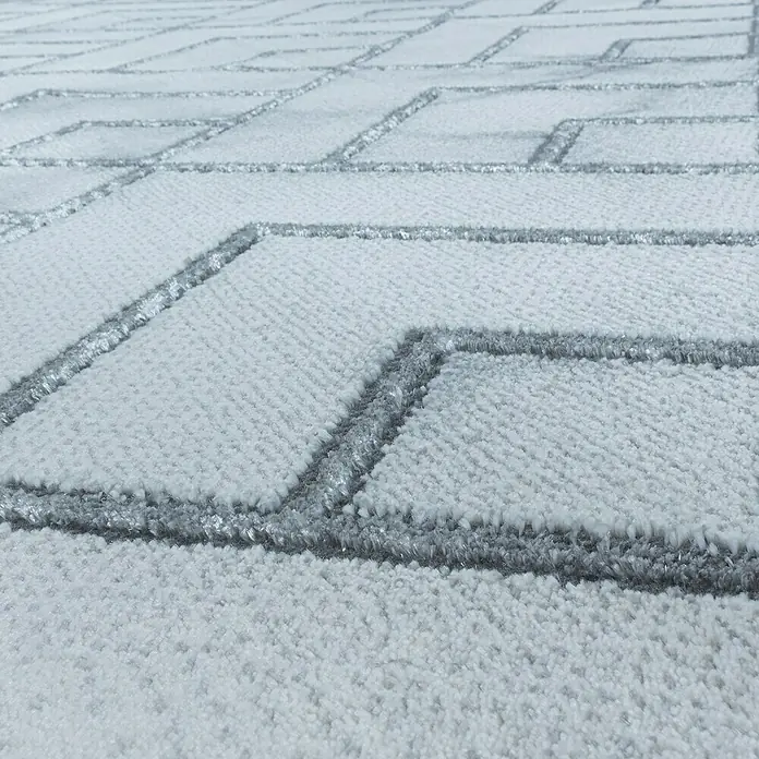 Kurzflorteppich Naxos 3813Silber, 200 x 140 cm, 80% Polypropylen, 20% Polyester - Detailaufnahme eines weißen Teppichs mit geometrischem Muster. Die hellgrauen Linien bilden ein elegantes Design auf dem flauschigen Untergrund.