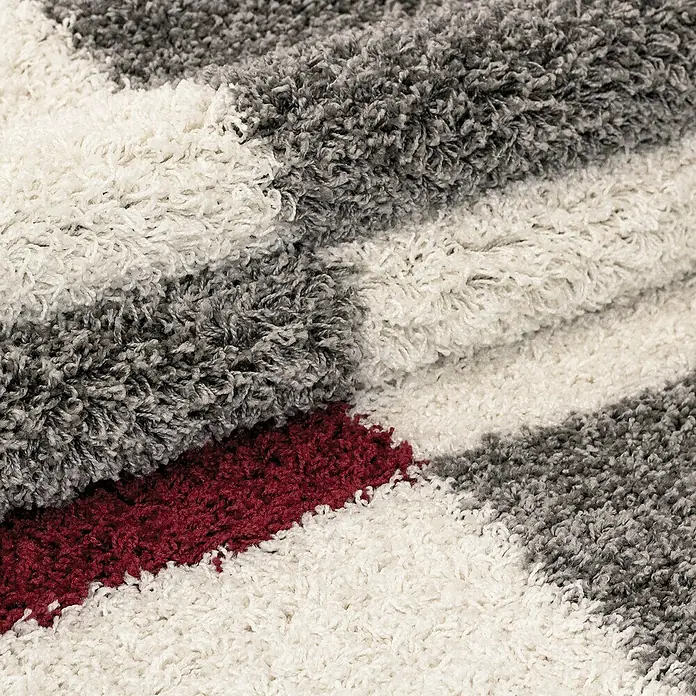 Hochflorteppich Gala 2505Rot, 110 x 60 cm, 100 % Polypropylen - Detailaufnahme eines weichen Teppichs mit Streifen in Grau, Weiß und Burgunderrot, der eine gemütliche Textur und ein ansprechendes Design bietet.