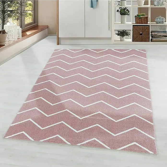 Hochflorteppich Rio 4602 - Rose, 200 x 140 cm, 100% Polypropylen - Ein rosa Teppich mit Zickzackmuster liegt in einem hellen Raum. Der Teppich verleiht dem Raum eine spielerische und moderne Note.