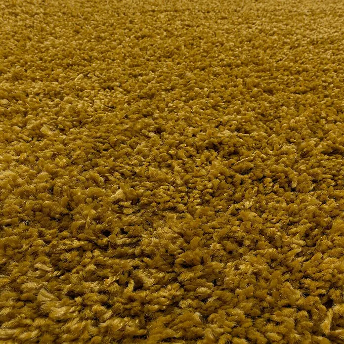 Hochflorteppich Sydney 3000Gold, Durchmesser: 120 cm, 100% Polypropylen - Detailaufnahme eines ockergelben Shaggy-Teppichs, der eine weiche und flauschige Textur zeigt.