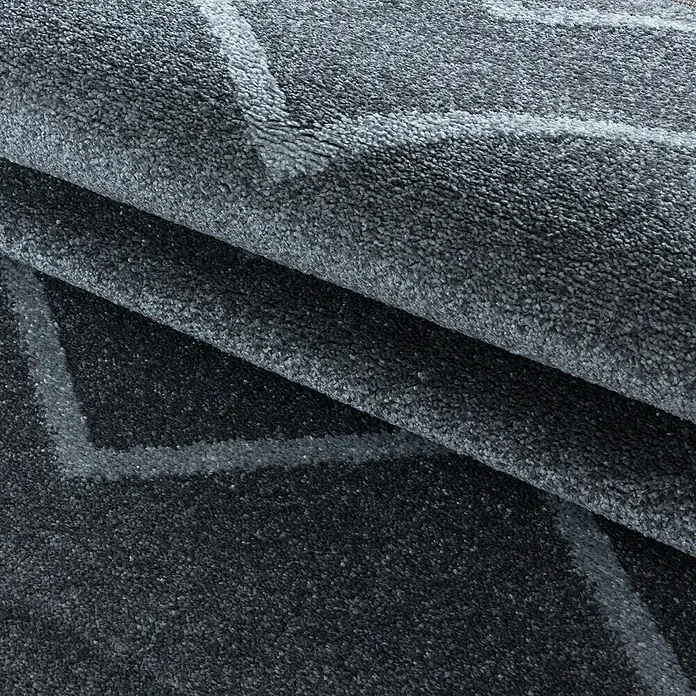 Hochflorteppich Rio 4602Grau, 250 x 80 cm, 100% Polypropylen - Nahaufnahme eines dunkelgrauen Teppichs mit hellgrauen geometrischen Mustern und gefalteter Textur.