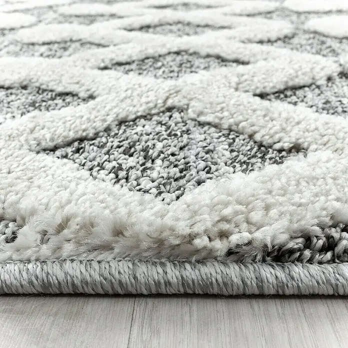 Hochflorteppich Pisa 4710Grau, 200 x 140 cm, 100 % Polypropylen - Nahaufnahme eines strukturierten Teppichs mit einem eleganten, sich wiederholenden Rautenmuster in Grau- und Weißtönen, ideal für modernes Wohndesign.