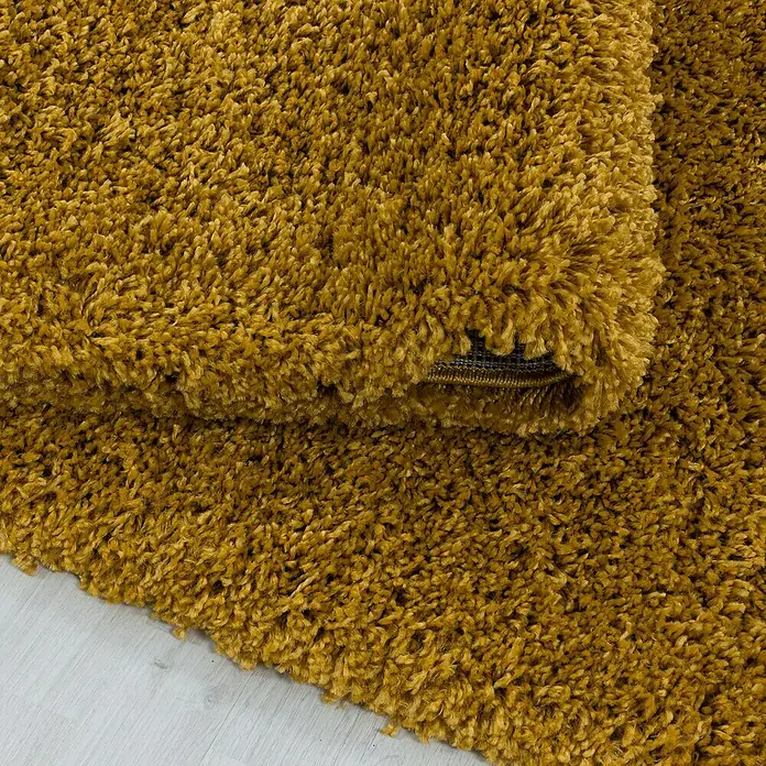 Hochflorteppich Sydney 3000Gold, 250 x 80 cm, 100% Polypropylen - Nahaufnahme eines goldfarbenen Zottelteppichs, der eine weiche und luxuriöse Textur für ein gemütliches Ambiente zeigt.