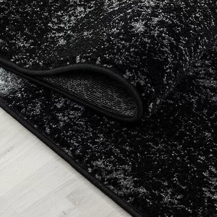 Kurzflorteppich Hawaii 1330 - Schwarz, 170 x 120 cm, 100% Polypropylen - Schwarz-grau gemusterter Teppich, teilweise aufgerollt, zeigt die weiche Oberfläche und den Abschlussrand.