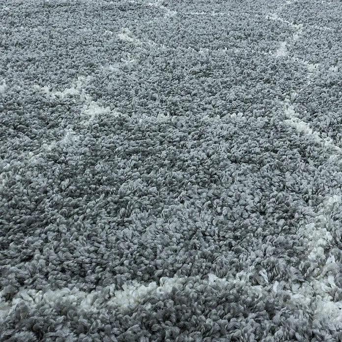 Hochflorteppich Salsa 3201Grau, 110 x 60 cm, 100% Polypropylen - Nahaufnahme eines grauen und weißen Shaggy-Teppichs, der eine weiche und einladende Textur zeigt. Ideal, um jedem Raum Wärme und Komfort zu verleihen.