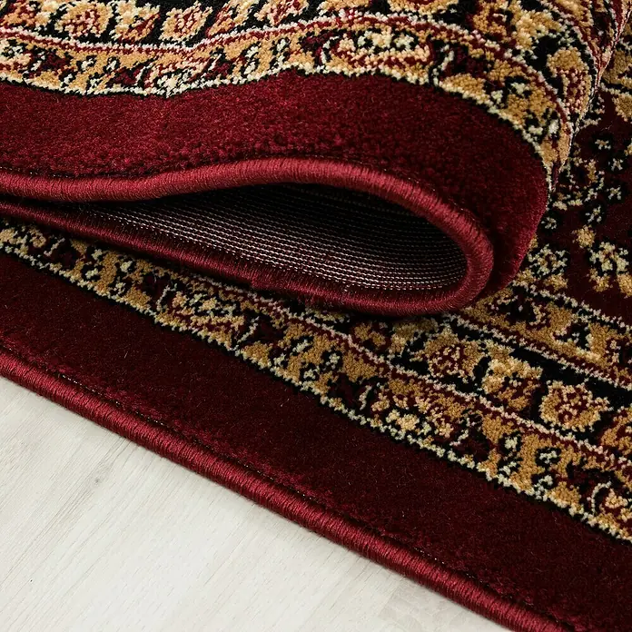 Kurzflorteppich Orient-Optik Marrakesh 0207 - Rot, 150 x 80 cm, 100 % Polypropylen - Nahaufnahme eines opulenten, burgunderroten Teppichs mit kunstvollen goldenen und schwarzen Mustern, der eine elegante und warme Atmosphäre verspricht.