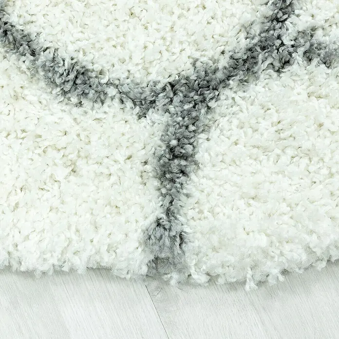 Hochflorteppich Salsa 3201 - Cream, 250 x 80 cm, 100% Polypropylen - Nahaufnahme eines hochflorigen Teppichs mit geometrischem Muster in Weiß und Grau, der eine weiche und luxuriöse Textur zeigt.