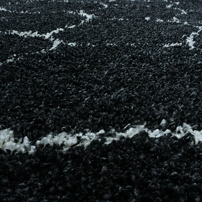 Hochflorteppich Salsa 3201Anthrazit, 290 x 200 cm, 100% Polypropylen - Nahaufnahme eines schwarzen Teppichs mit weißen Linien, der eine weiche und luxuriöse Textur für Ihr Zuhause bietet.