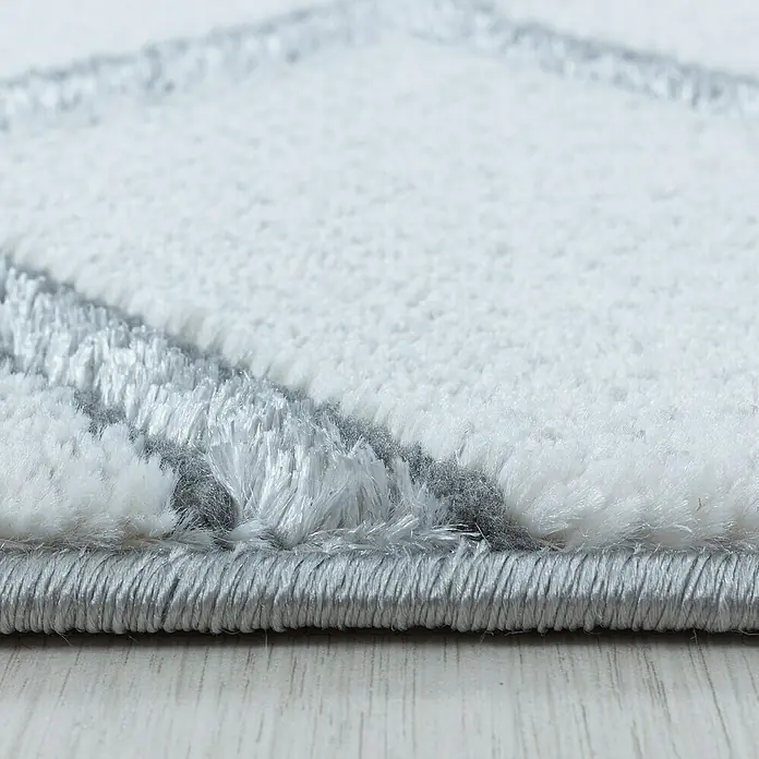 Kurzflorteppich Naxos 3813Silber, 200 x 140 cm, 80% Polypropylen, 20% Polyester - Detailaufnahme eines weißen Teppichs mit grauem Muster, der die Textur und die hochwertige Verarbeitung hervorhebt.