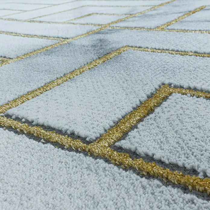 Kurzflorteppich Naxos 3813 - Gold, 200 x 140 cm, 80% Polypropylen, 20% Polyester - Detailansicht eines modernen Teppichs mit geometrischem Muster in Grau und Gold. Der Teppich zeichnet sich durch seine hochwertige Verarbeitung aus.