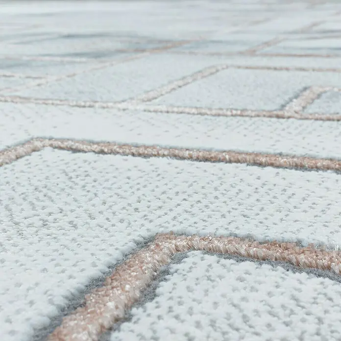 Kurzflorteppich Naxos 3813Bronze, 200 x 140 cm, 80% Polypropylen, 20% Polyester - Nahaufnahme eines Teppichs mit geometrischem Muster in Weiß und Beige. Der Teppich hat eine weiche Textur und ein elegantes Design.