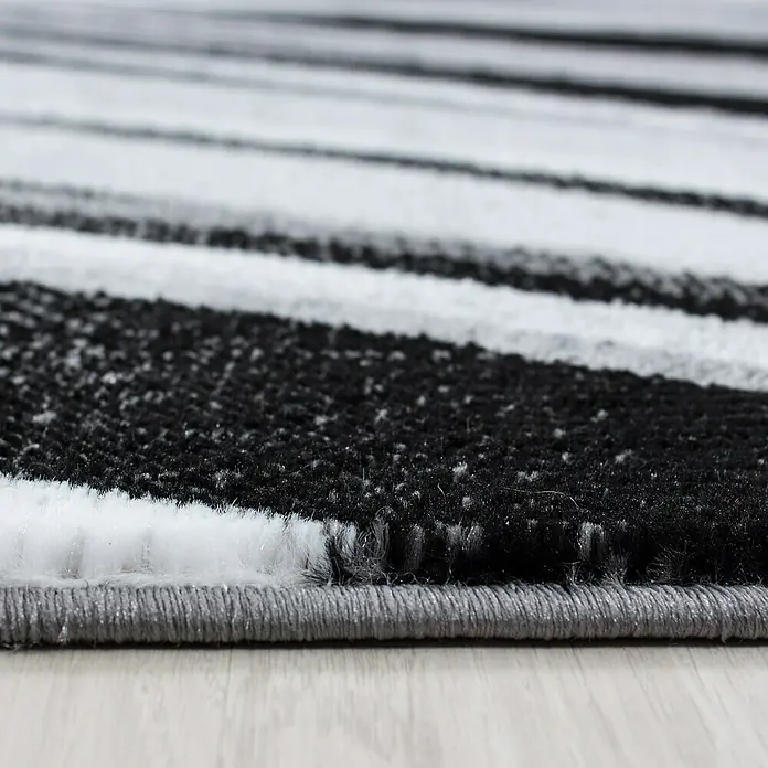 Kurzflorteppich Parma 9210Schwarz, 170 x 120 cm, 100% Polypropylen - Nahaufnahme eines Teppichs mit schwarzen und weißen Streifen, der Textur und Tiefe zeigt. Das moderne Design verleiht jedem Raum einen Hauch von Stil.