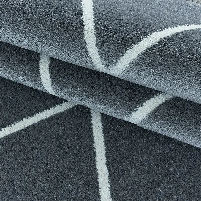 Hochflorteppich Rio 4601 - Silber, 150 x 80 cm, 100 % Polypropylen - Nahaufnahme eines grauen Teppichs mit weißem geometrischem Muster, kunstvoll gefaltet, um seine Textur und sein Design hervorzuheben.