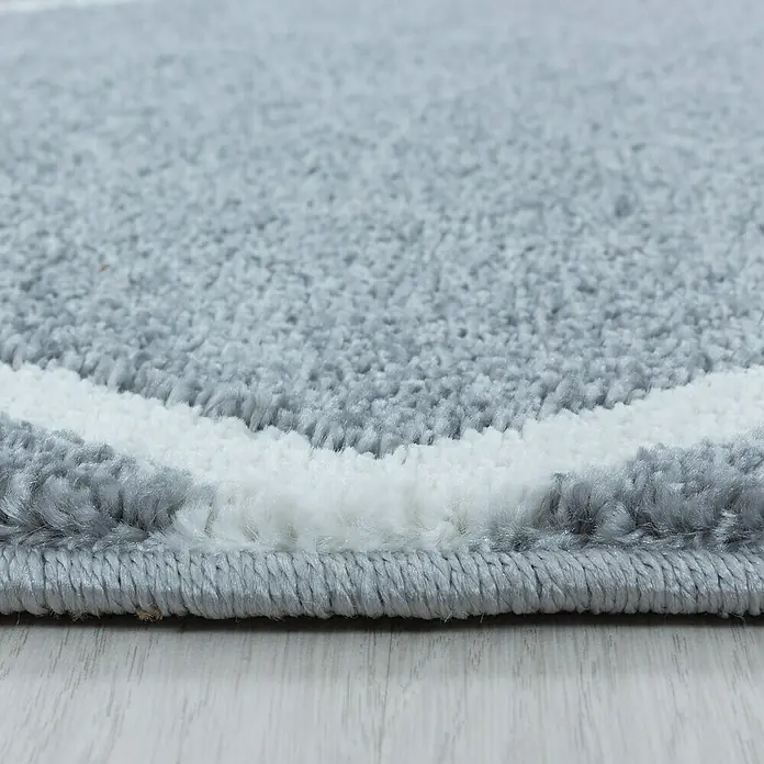 Hochflorteppich Rio 4601 - Silber, 150 x 80 cm, 100 % Polypropylen - Nahaufnahme eines grauen Teppichs mit weißem Streifen und detaillierter Kante, der die Textur und Verarbeitung hervorhebt.