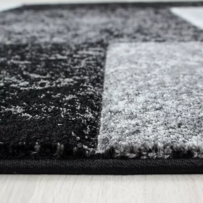 Kurzflorteppich Hawaii 1330 - Schwarz, 170 x 120 cm, 100% Polypropylen - Nahaufnahme eines schwarz-grau-weißen Kurzflor-Teppichs mit abstraktem Muster auf hellem Boden.