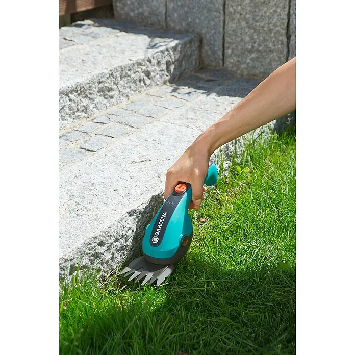 Gardena ClassicCut Akku-Gras- & Strauchschere - 3,6 V, Li-Ionen, 1 Akku, Schwertbreite: 8 cm - Gardena Akku-Grasschere im Einsatz, um Rasen an einer Steintreppe zu trimmen. Das Werkzeug ist türkis und schwarz.