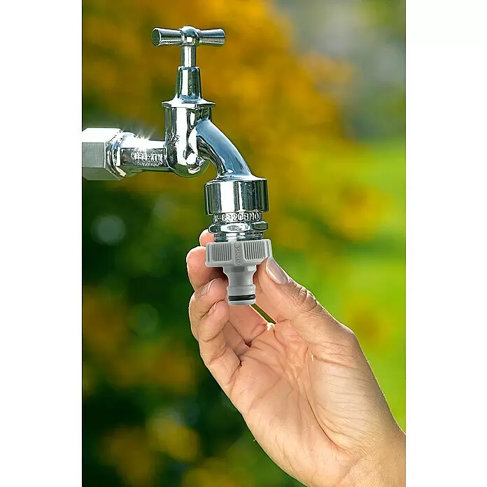 Gardena Hahnverbinder - Passend für: G 3/8″ Wasserhahn mit G 1/2″ Gewinde, Einsatzbereich: Bewässerungstechnik - Hand befestigt grauen Schlauchverbinder an einem Chrom-Außenwasserhahn.