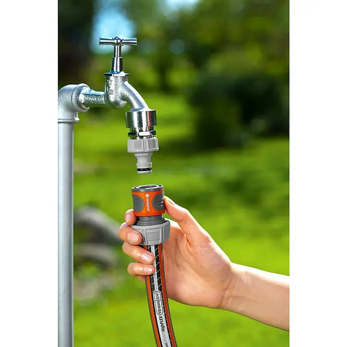 Gardena Schlauchverbinder Satz - ¾″ - Ein Gardena-Gartenschlauch wird an einen Wasserhahn angeschlossen. Der Schlauch ist orange und grau, mit einem "HighFlex"-Aufdruck.