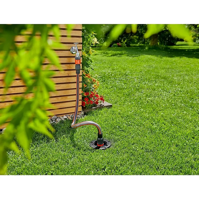 Gardena Sprinklersystem Wassersteckdose - ¾″ - Eine moderne Wasserzapfsäule aus Edelstahl und Kunststoff in einem grünen Garten, ideal für die Gartenbewässerung.