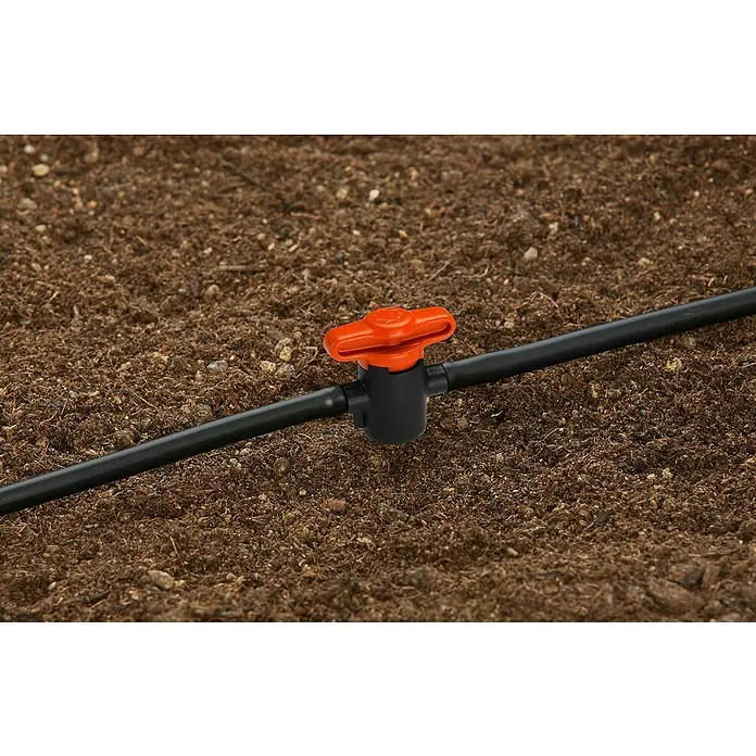 Gardena Micro-Drip Absperrventil - ³⁄₁₆″ - Nahaufnahme eines Bewässerungssystems mit einem orangefarbenen Ventil in einem Garten.