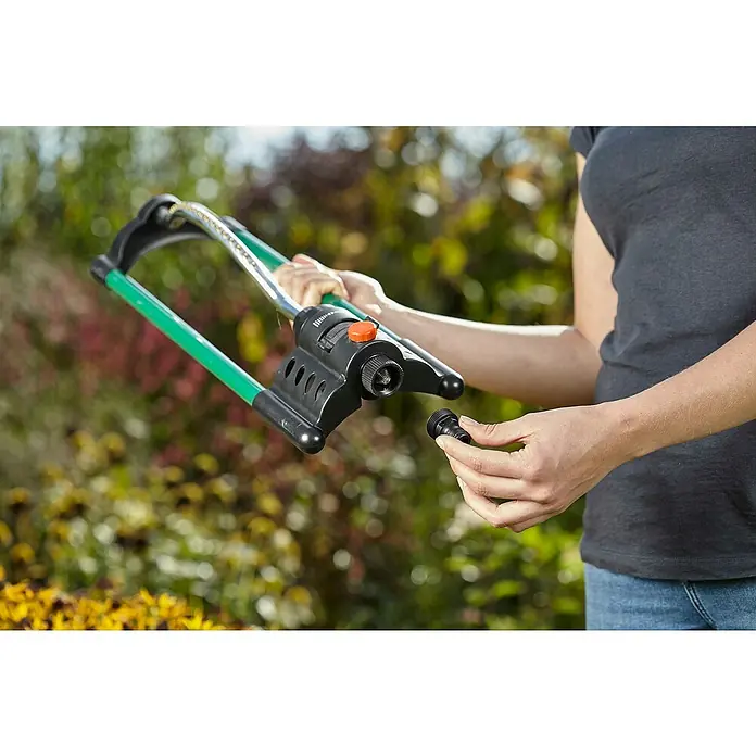 Gardena SB-System Gerätestück - 26,5 mm (G 3/4“) - Nahaufnahme einer Person, die einen Rasensprenger mit oszillierendem Sprüharm und schwarzem Anschlussstück in der Hand hält, bereit für den Einsatz.