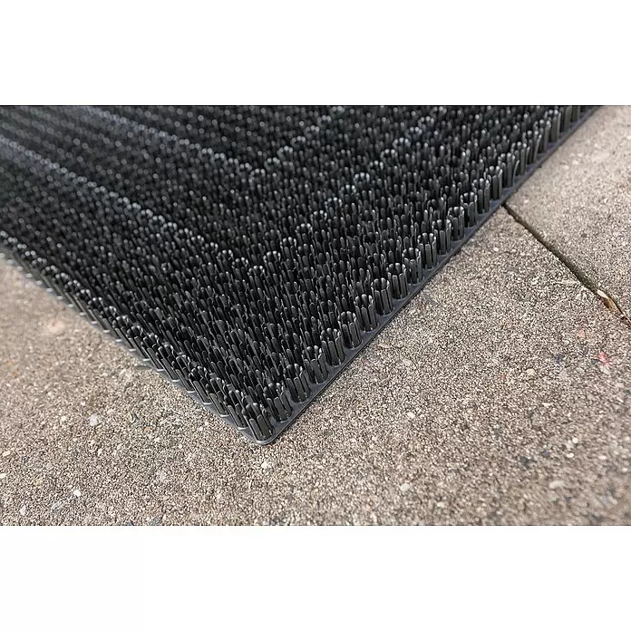 Astra Universalmatte Season - 40 x 60 cm, Schwarz, Material Nutzschicht: 100 % Polyethylen - Schwarze Kunststoff-Drainagematte mit zahlreichen zylindrischen Noppen, auf einer strukturierten Betonfläche.