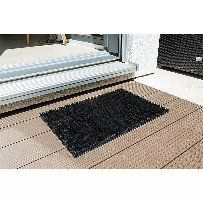 Astra Universalmatte Season - 40 x 60 cm, Schwarz, Material Nutzschicht: 100 % Polyethylen - Schwarze Stoppel-Fußmatte auf Holzterrasse vor einer Außenschiebetür, zur Schuhreinigung.