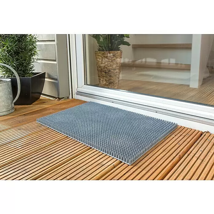 Astra Universalmatte Season - 40 x 60 cm, Grau, Material Nutzschicht: 100 % Polyethylen - Graue Fußmatte mit zahlreichen Gumminoppen auf einer Holzterrasse vor einer Glastür.