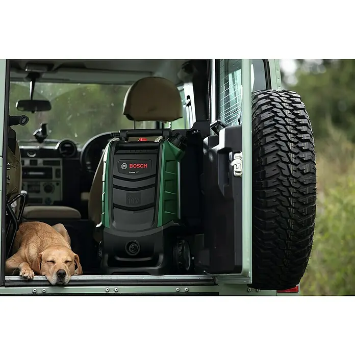 Bosch Power for All 18V Akku-Hochdruckreiniger Fontus - 18 V, Ohne Akku, Max. Druck: 20 bar - Der Bosch Fontus 18V Akku-Reiniger im Kofferraum eines Geländewagens, neben einem schlafenden Hund und einem Reserverad.