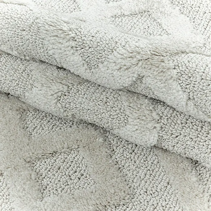 Hochflorteppich Pisa 4708Cream, 110 x 60 cm, 100% Polypropylen - Nahaufnahme eines weichen, gefalteten Badteppichs mit geometrischem Muster in sanften Grautönen. Ideal für ein stilvolles Badezimmer.