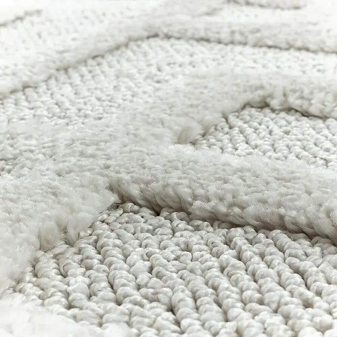 Hochflorteppich Pisa 4708Cream, Durchmesser: 120 cm, 100% Polypropylen - Nahaufnahme eines weißen Teppichs mit unterschiedlichen Texturen, die ein luxuriöses und weiches Gefühl vermitteln.