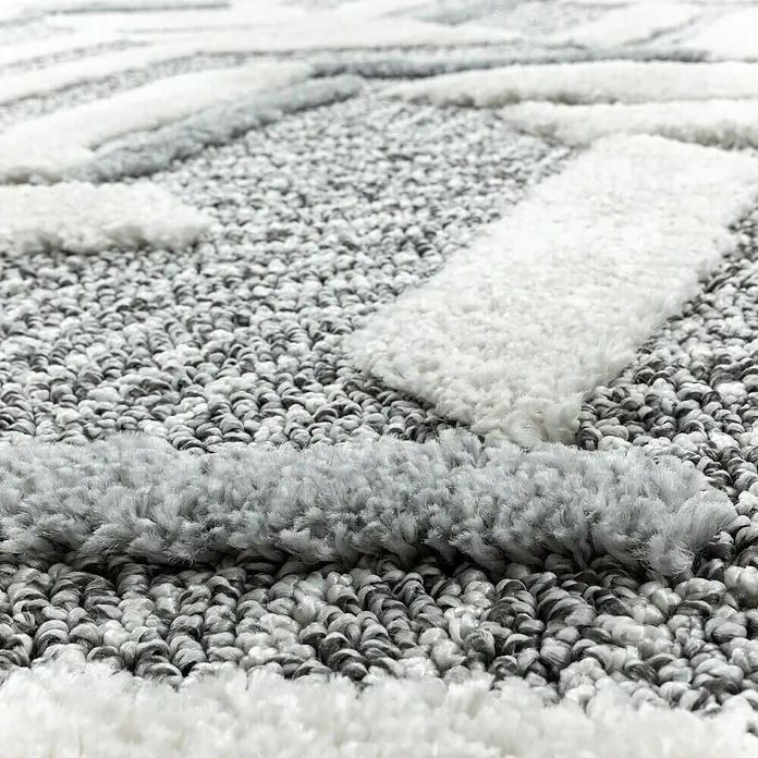 Hochflorteppich Pisa 4705Grau, Durchmesser: 80 cm, 100% Polypropylen - Nahaufnahme eines Teppichs mit abstraktem Muster in Grau- und Weißtönen.