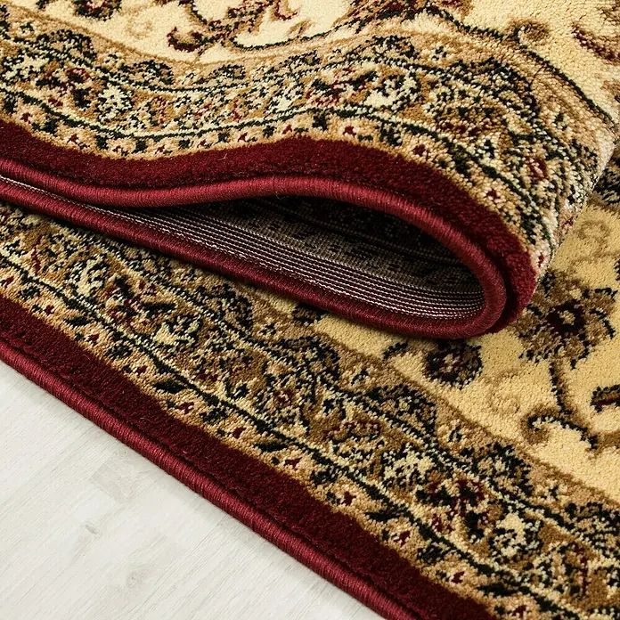 Kurzflorteppich Orient-Optik Marrakesh 0210Rot, 170 x 120 cm, 100% Polypropylen - Detailansicht eines eleganten, gewundenen Perserteppichs mit einem reichen, ornamentalen Muster und einer tiefroten Bordüre.