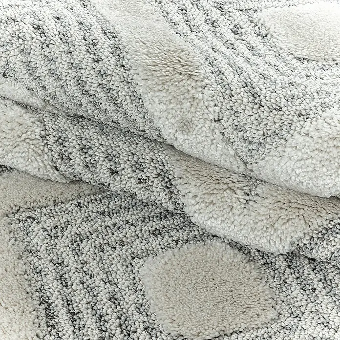 Hochflorteppich Pisa 4707Grau, 150 x 80 cm, 100% Polypropylen - Detailaufnahme eines flauschigen grauen Teppichs mit hellen, runden Akzenten, der Textur und Komfort ausstrahlt.